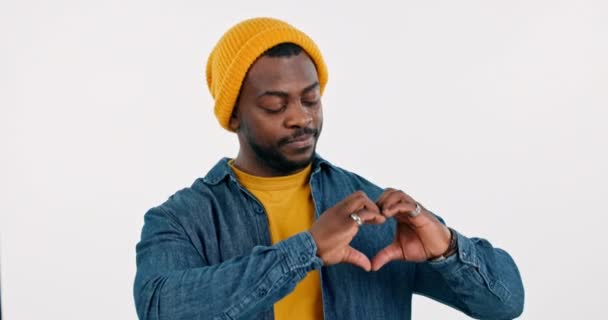 Hart, handen en gezicht van de zwarte man in de studio voor vriendelijkheid, zorg en liefdadigheid donatie op witte achtergrond. Gelukkige portret, mode en herziening van liefde, hoop en dank voor steun, emoji teken en vrede. - Video