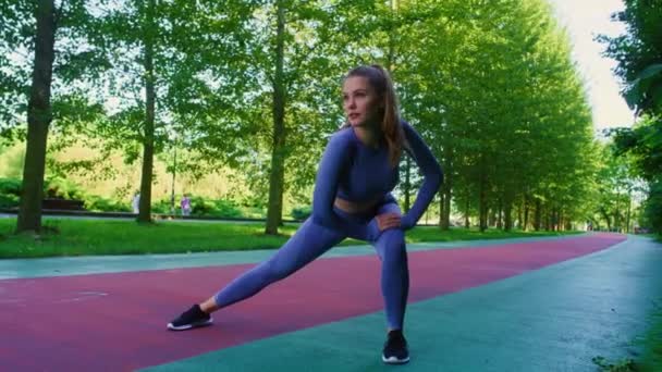 公園でジョギングする前に伸びている若い白人女性のワイドショット. 8KでREDヘリウムカメラで撮影する.   - 映像、動画