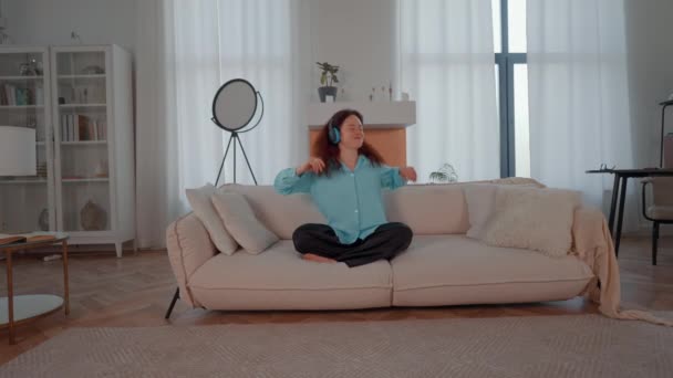 Frau mit Kopfhörer auf dem Kopf hört Lieblingslied tanzen Musik zu Hause genießen - Filmmaterial, Video