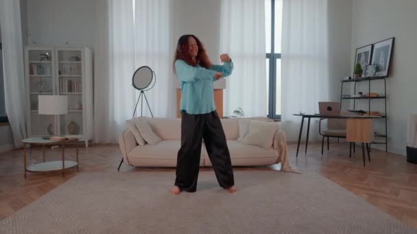 podekscytowana kobieta słuchająca muzyki tańczącej w domu za pomocą słuchawek cieszyć się wolnością - Materiał filmowy, wideo