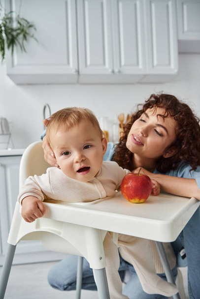 szerető anya néz baba lánya ül babakocsin közel érett friss alma, boldog szülőség - Fotó, kép