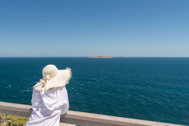 Donna che indossa camicia bianca con cappello bianco guardando nell'oceano a Cape Spencer, penisola di Yorke, Australia Meridionale - Foto, immagini