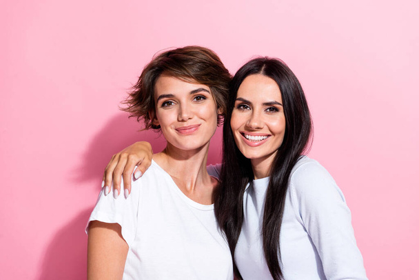 Photo of two positive nice cute girls dressed white outfit hugging together isolated on pink color background. - Photo, Image
