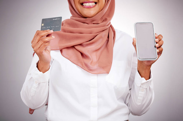 Woman, credit card and phone screen for online shopping, muslim fashion marketing and e commerce in studio. Islamic customer in hijab, mobile mockup and banking app for payment on a white background. - Foto, Bild