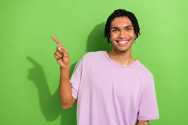 Photo of nice satisfied young man toothy smile indicate finger empty space isolated on green color background. - Foto, immagini