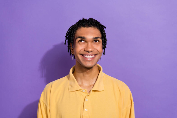 Photo of dreamy optimistic person with piercing wear stylish shirt look up at promo empty space isolated on purple color background. - Фото, изображение