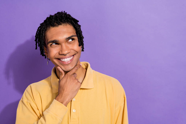 Photo of optimistic person with cornrows wear stylish shirt look empty space offer finger on chin isolated on purple color background. - Fotó, kép
