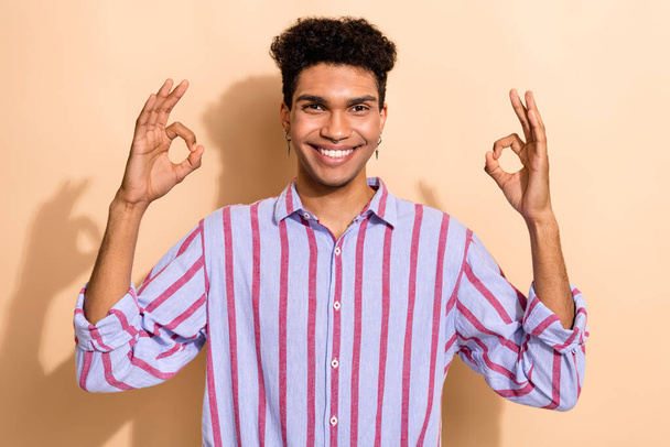 Portrait of handsome young worker guy wearing formal clothes showing okay symbol hands isolated beige color background. - 写真・画像