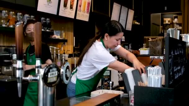 Starbucks в Канаді у Ванкувері готує каву різних напоїв позаду контр-жінки в білих фартухах футболок  - Кадри, відео