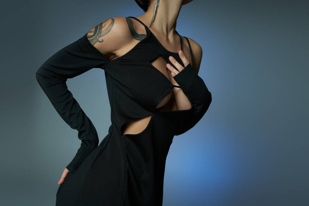 recortado vista de seductora mujer tatuada en traje gótico azul gris telón de fondo, concepto de Halloween - Foto, Imagen