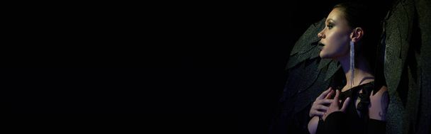 готична краса, вид збоку жінки в костюмі Хеллоуїна темного демона з крилами на чорному, банер - Фото, зображення