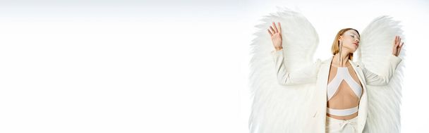 divine beauty, woman in costume of light winged angel standing with closed eyes on white, banner - Photo, Image