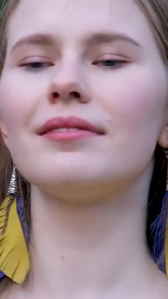 jeune belle femme, jeune fille dans la grande ville en chemise brodée jaune, chemisier brodé, cheveux longs bruns, boucles d'oreilles en plumes sourire, couleurs jaunes et bleues dans les vêtements, costume national ukrainien - Séquence, vidéo