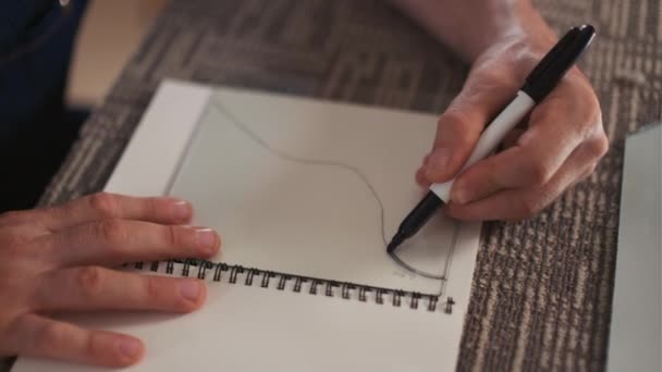 Primer plano de las manos del manitas destacando la línea en un trozo de vidrio mientras está sentado en el escritorio del taller - Metraje, vídeo