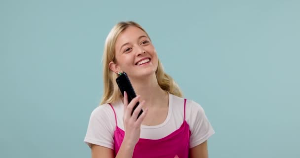 Žena, telefonát a komunikace ve studiu, šťastný s úsměvem a smartphone s chatem na modrém pozadí. Mockup prostor, legrační konverzace a VOIP s technologií, sítí a připojením. - Záběry, video