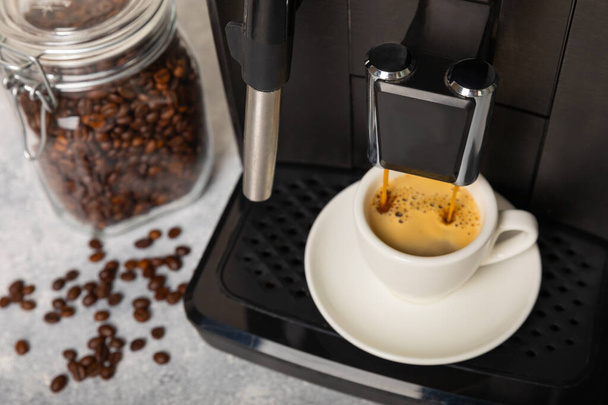 Moderne koffiezetapparaat met een kopje op de keukentafel. Koffiehuis. Moderne espressomachine met een kopje in de keuken. Bereiding van een geurige warme drank. Plaats voor tekst.Kopieer ruimte. - Foto, afbeelding