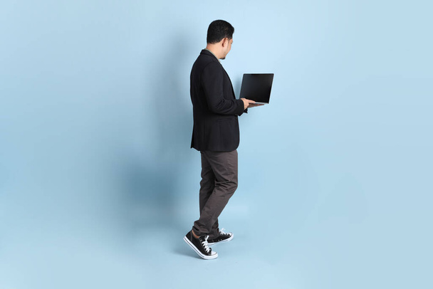 Взрослый бизнесмен азиат в умной повседневной одежде, стоящий на зеленом фоне. - Фото, изображение