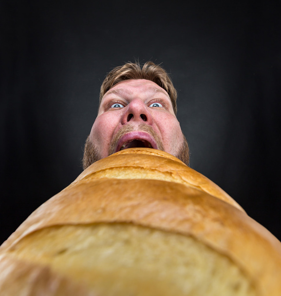 Чоловік їсть великий хліб
 - Фото, зображення