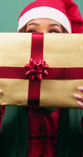 Νεαρή γυναίκα κρύβεται πίσω από χριστουγεννιάτικο δώρο, αποκαλύπτοντας τα μάτια, στούντιο βίντεο. Υψηλής ποιότητας 4k πλάνα - Πλάνα, βίντεο