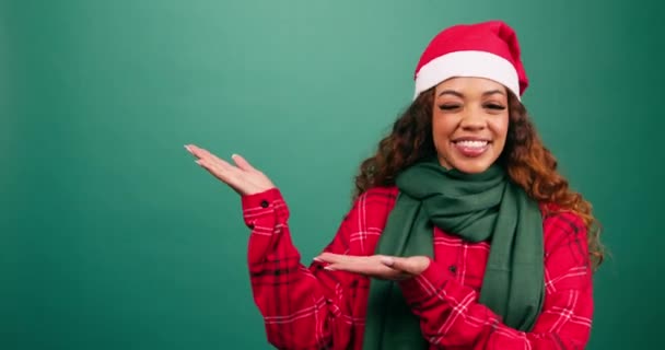 Schöne junge Frau zeigt nach links zum Kopierraum, Weihnachtsmann-Hutatelier. Hochwertiges 4k Filmmaterial - Filmmaterial, Video