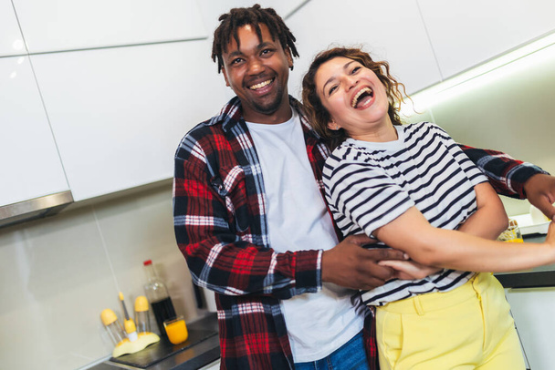 Multiracial couple dancing salsa in the kitchen - Foto, Bild