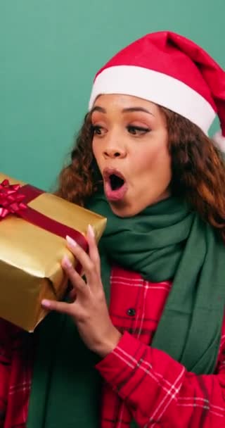 Opgewonden jonge vrouw schudt kerstcadeau, raden wat erin zit, Studio. Hoge kwaliteit 4k beeldmateriaal - Video