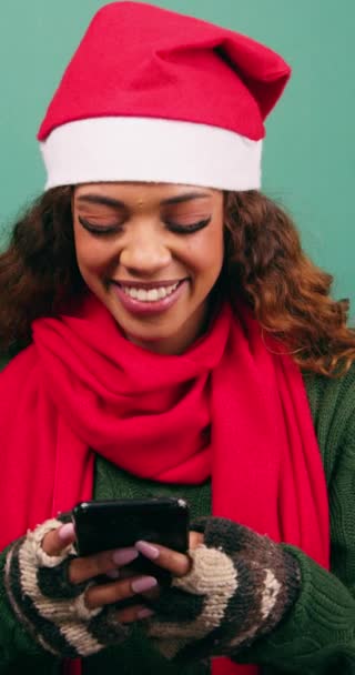 Krásná mladá žena v Santa klobouk texty a používá telefon smích, vánoční studio. Vysoce kvalitní 4K záběry - Záběry, video