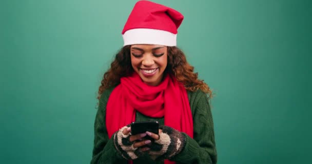 Noel Baba şapkalı güzel genç bir kadın mesaj atıyor ve telefonuyla gülüyor, Xmas stüdyosunda. Yüksek kalite 4k görüntü - Video, Çekim