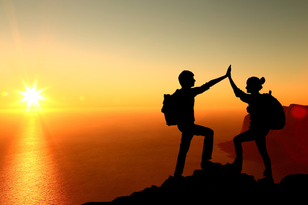 die Silhouette von zwei Mann mit Erfolgsgeste, die auf dem Gipfel des Berges stehen - Foto, Bild