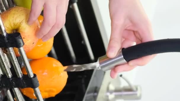 Una mujer lava una manzana sobre el fregadero de la cocina mientras prepara un desayuno con fruta fresca. Concepto de comida saludable. Vídeo vertical - Imágenes, Vídeo