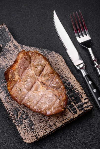 Délicieux steak de porc ou de bœuf juteux cuit sur le gril avec du sel et des épices sur un fond de béton texturé - Photo, image