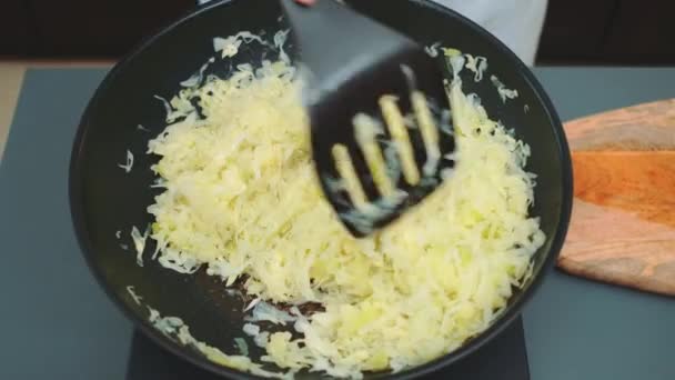 Ανακατέψτε το λάχανο με μια σπάτουλα κουζίνας. Βραστό λάχανο σε τηγάνι. Κάτοψη του τραπεζιού της κουζίνας. Μαγείρεμα στην κουζίνα - Πλάνα, βίντεο