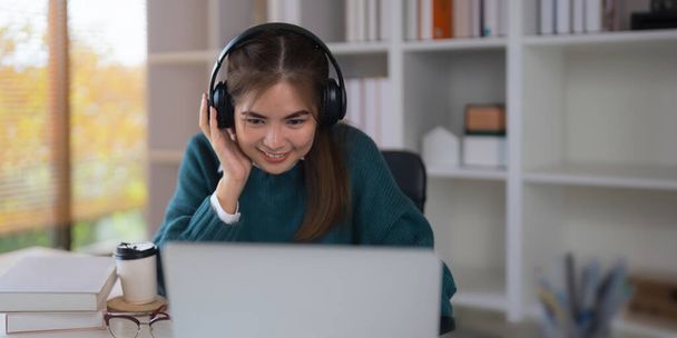 Online učení. veselá školní studentka studuje pomocí digitálního notebooku a bezdrátových sluchátek doma. - Fotografie, Obrázek