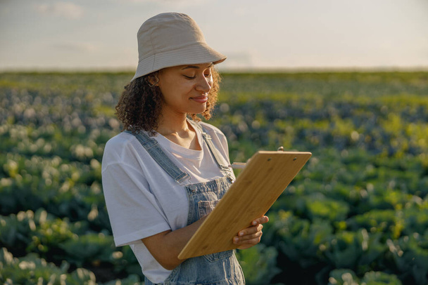 Жінка-фермер в уніформі, що працює на капустяному полі під час збору врожаю. Сільськогосподарська діяльність - Фото, зображення