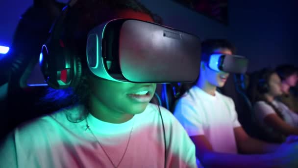Black teen girl in VR headset playing video games in video game club with illumination - Footage, Video