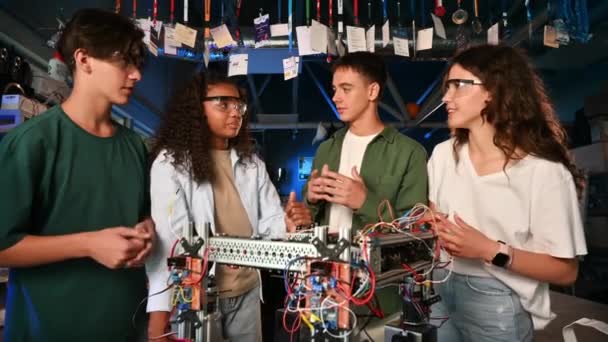 Grupo de jóvenes discutiendo y haciendo experimentos en robótica en un laboratorio. Robot sobre la mesa - Imágenes, Vídeo
