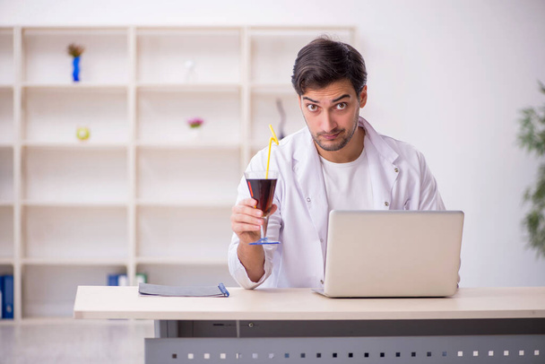 Молодой химик изучает безалкогольный напиток в лаборатории - Фото, изображение