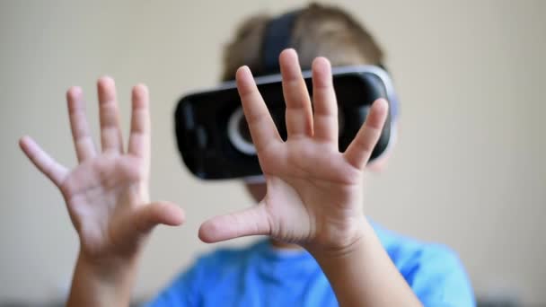 Blond jongetje dat thuis een virtual reality headset draagt. Kijkend naar zijn handen en gebaren. Langzame beweging - Video