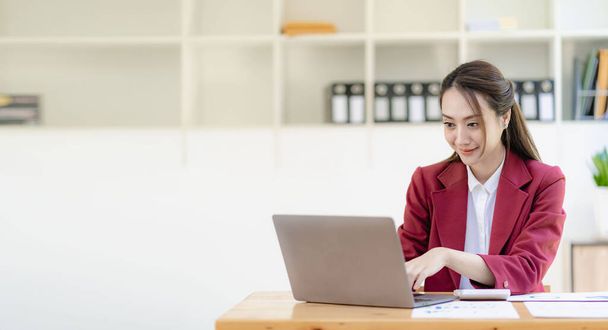 Asian businesswoman working with papers and laptop sitting at table in office, analyzing business accounting calculations and financial planning concepts. - Valokuva, kuva