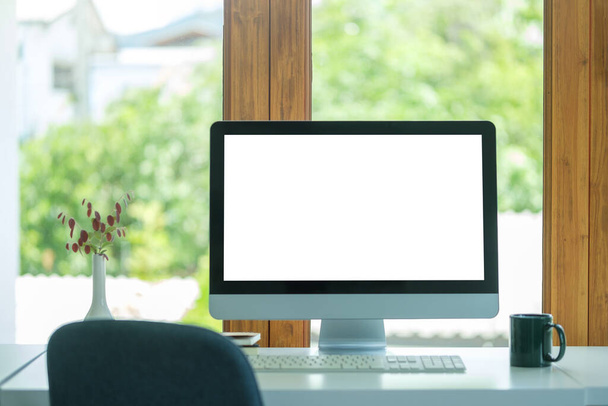 Порожній екран монітора, чашка кави і горщик рослини на білому столі в яскравому офісі. - Фото, зображення