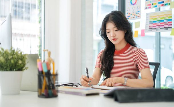 Стильная молодая женщина с графическим планшетом и стилизованной ручкой, работающая над новым проектом в домашнем офисе. - Фото, изображение