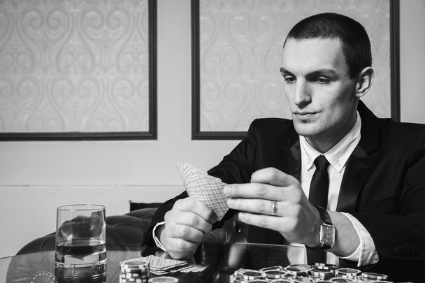Ο νεαρός άντρας στο καζίνο στο τραπέζι του παιχνιδιού - Φωτογραφία, εικόνα