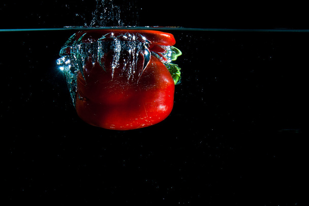 Pepper dropped into water. - Фото, изображение