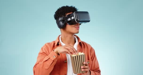 Man, popcorn en virtual reality, 3D film en ervaring met digitale wereld en entertainment op blauwe achtergrond. VR, metaverse en fantasie, het eten van maïssnack en holografische met tech in de studio. - Video