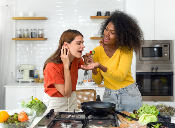 Entdecken Sie die herzerwärmende Verbindung zwischen zwei Frauen, die in eine lebhafte Diskussion verwickelt sind, während sie in einer gut beleuchteten Küche stehen und die Schönheit sinnvoller Verbindungen und Freundschaft feiern. - Foto, Bild