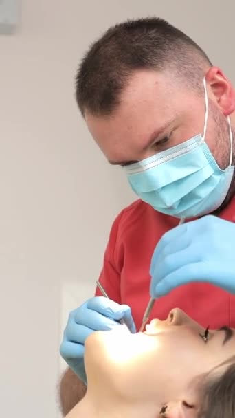 Schöne junge Frau mit Zahnbehandlung in Zahnarztpraxis. Der Zahnarzt behandelt die Zähne der Patienten. Vertikales Video - Filmmaterial, Video
