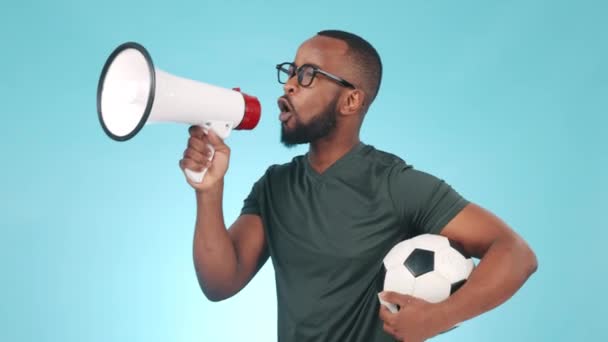 Football coach, man and megaphone in blue studio background, shouting and cheering with passion, pointing and energy. Soccer ball, person and loud voice for motivation, goals and team winning streak. - Footage, Video