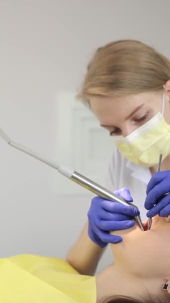 Zubař ošetřuje zubaře na zubní klinice. Lidé, medicína, stomatologie a koncepce zdravotní péče. Zubař provádí stomatologické ošetření pacienta. Svislé video - Záběry, video