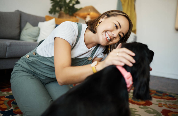 Love, smile and woman with dog in home lounge to relax and play with animal. Pet owner, happy and asian person on floor with companion, care and wellness or friendship and together in cozy apartment. - Photo, Image