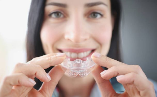 Donna sorridente tiene paradenti in plastica trasparente per raddrizzare i denti. Correzione del morso e concetto di bruxismo - Foto, immagini